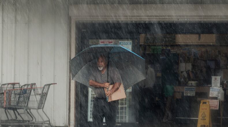 A resident carries supplies during Hurricane Lala in Hawaiian Ocean View, Hawaii, Saturday, Aug. 15, 2026. (Stephen Lam/San Francisco Chronicle via AP)