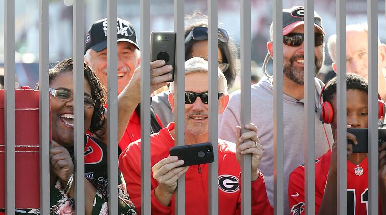 Georgia fans angle for a view and snap photos through the fence while the Georgia official team photo is taken at Rose Bowl Stadium on Sunday, December 31, 2017, in Pasadena. Curtis Compton/ccompton@ajc.com