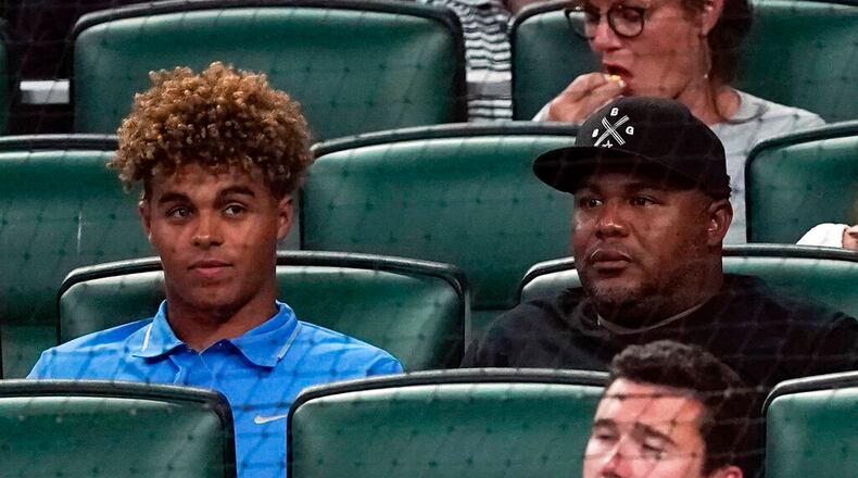 Druw Jones (left) sits with his dad, former Braves great Andruw Jones, during a game between Athletics and the Braves on Tuesday, June 7, 2022, in Atlanta. (AP Photo/John Bazemore)