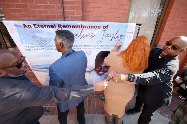 Attendees of the memorial service of Cornelius Taylor sign a remembrance banner before entering Ebenezer Baptist Church. (Miguel Martinez/AJC 2025)