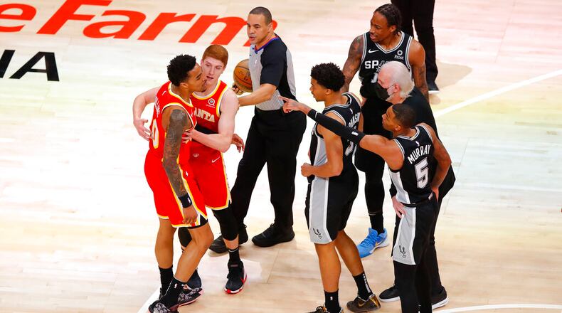 Atlanta Hawks forward John Collins (20) is separated from San Antonio Spurs forward DeMar DeRozan (10) by Hawks guard Kevin Huerter as Spurs forward Keldon Johnson (3) and guard Dejounte Murray (5) come to DeRozan's defense during the first half of an NBA basketball game on Friday, Feb. 12, 2021, in Atlanta. (AP Photo/Todd Kirkland)