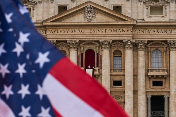 FILE - A flag from the United States waves from the crowd as Pope Leo XIV appears at the central balcony of St. Peter's Basilica for his first Sunday blessing after his election, in St. Peter's Square at the Vatican, Sunday, May 11, 2025.(AP Photo/Bernat Armangue, File)