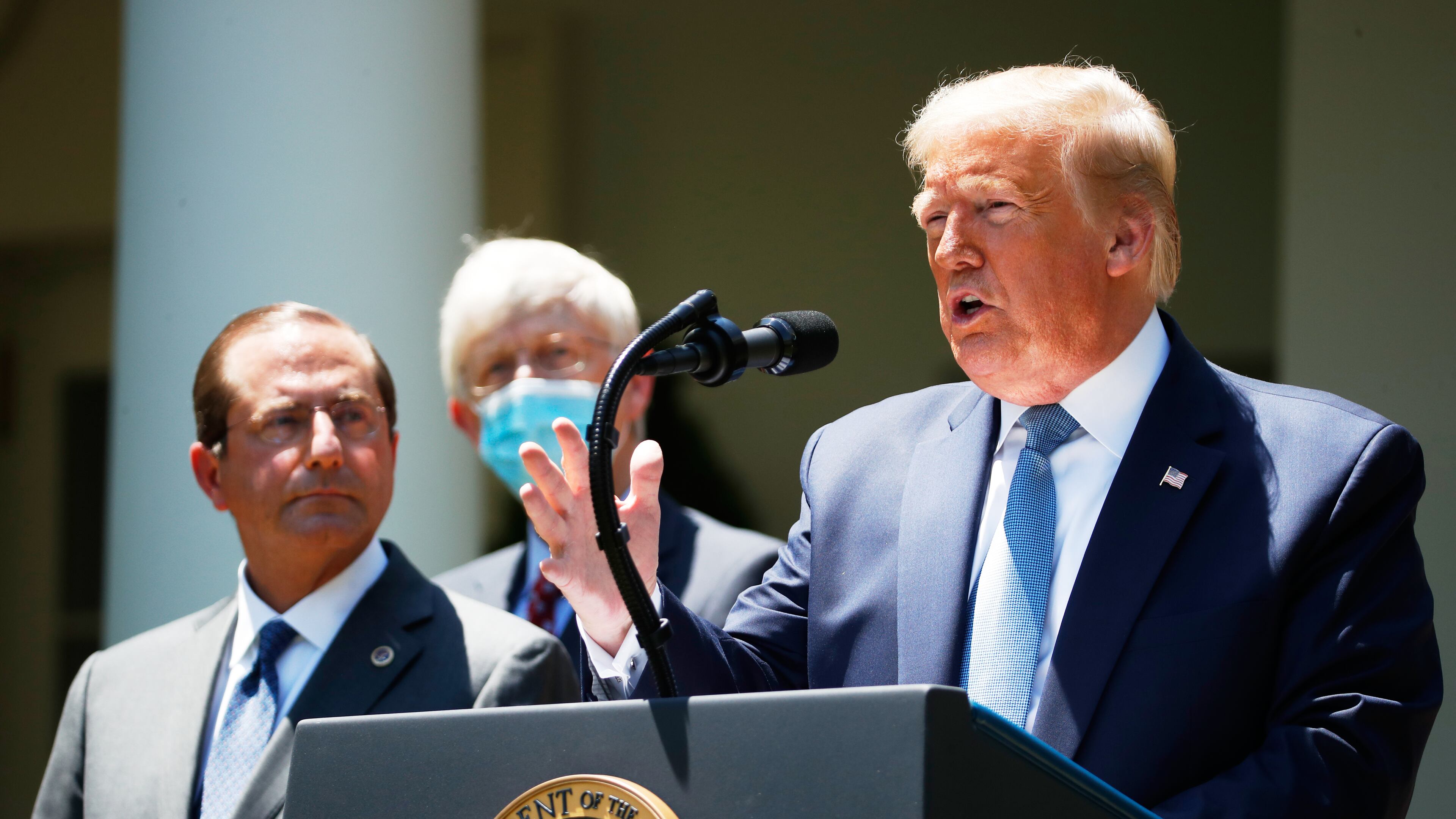 FILE - President Donald Trump speaks about the coronavirus in the Rose Garden of the White House, May 15, 2020, in Washington. Department of Health and Human Services Secretary Alex Azar, left, and Dr. Robert Redfield, director of the Centers for Disease Control and Prevention listen. (AP Photo/Alex Brandon, File)