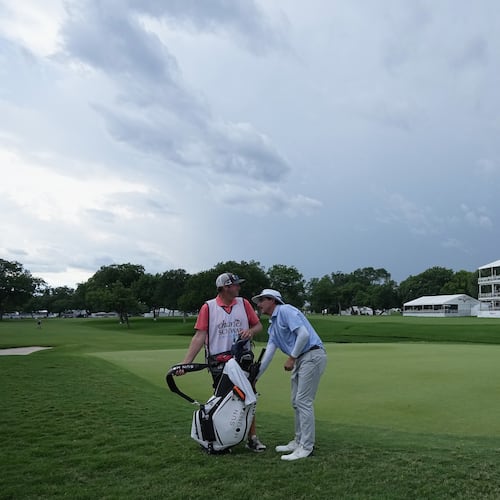 Joel Dahmen, right, reaches into his bag with caddie Jon Reehoorn on the 18th green after play was suspended due to weather during the first round of the Charles Schwab Challenge golf tournament at Colonial Country Club in Fort Worth, Texas, Thursday, May 28, 2026. (AP Photo/LM Otero)