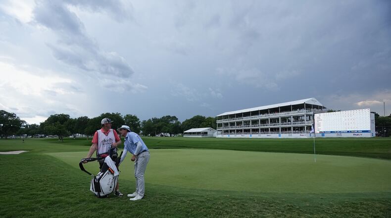 Joel Dahmen, right, reaches into his bag with caddie Jon Reehoorn on the 18th green after play was suspended due to weather during the first round of the Charles Schwab Challenge golf tournament at Colonial Country Club in Fort Worth, Texas, Thursday, May 28, 2026. (AP Photo/LM Otero)