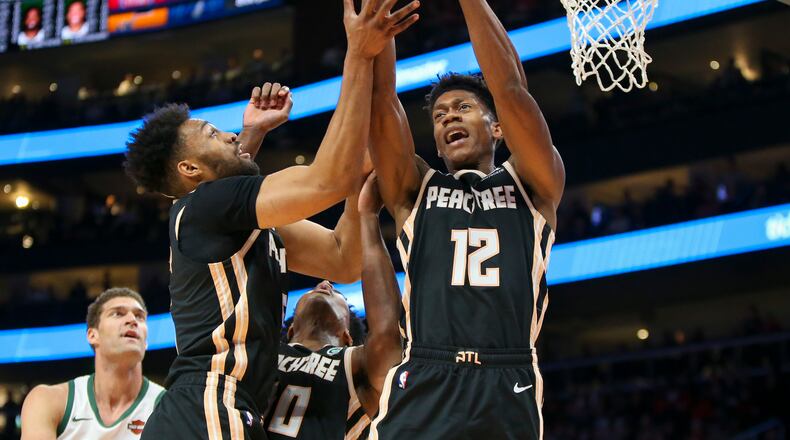 Atlanta Hawks forward Jabari Parker (5) and forward De'Andre Hunter (12) reach for a rebound against the Milwaukee Bucks in the first half of an NBA basketball game, Wednesday, Nov. 20, 2019, in Atlanta. (AP Photo/Brett Davis)