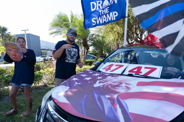 Supporters of President Donald Trump Jestin Nevarez, right, and Heather Dowling join a rally to support Elon Musk and the Department of Government Efficiency (DOGE) outside a Tesla car dealership, Saturday, April 12, 2025, in West Palm Beach, Fla. (AP Photo/Manuel Balce Ceneta)