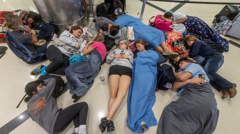 The CrowdStrike incident crippled Delta Air Lines for five days and caused 7,000 flight cancellations. Stranded travelers slept in airport terminals and struggled to reach their destinations, including these passengers at Hartsfield-Jackson International Airport on July 19. (John Spink/AJC)