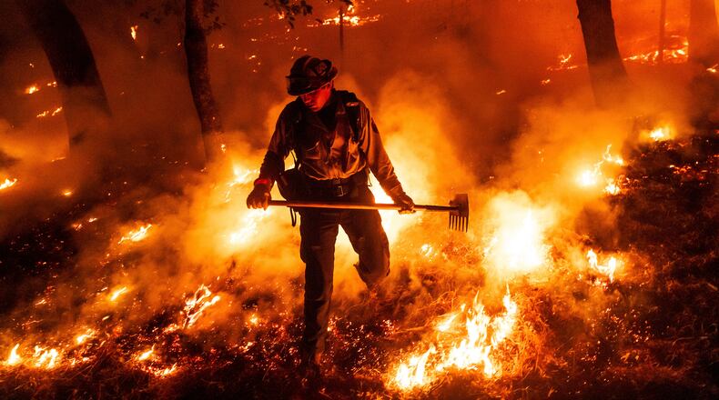 FILE - A firefighter battles the Pickett Fire burning in the Aetna Springs area of Napa County, Calif., Aug. 23, 2025. (AP Photo/Noah Berger, File)