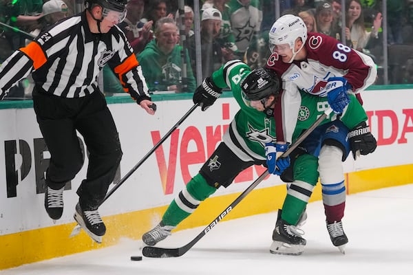 Colorado Avalanche center Martin Necas (88) and Dallas Stars center Sam Steel (18) compete for possession as referee Graham Skilliter (24) tries to get away during the first period in Game 2 of a first-round NHL hockey playoff series Monday, April 21, 2025, in Dallas. (AP Photo/Julio Cortez)