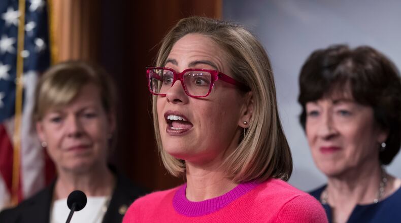 FILE - Sen. Kyrsten Sinema, D-Ariz., flanked by Sen. Tammy Baldwin, D-Wis., left, and Sen. Susan Collins, R-Maine, speaks to reporters following Senate passage of the Respect for Marriage Act, at the Capitol in Washington, Nov. 29, 2022. (AP Photo/J. Scott Applewhite, File)