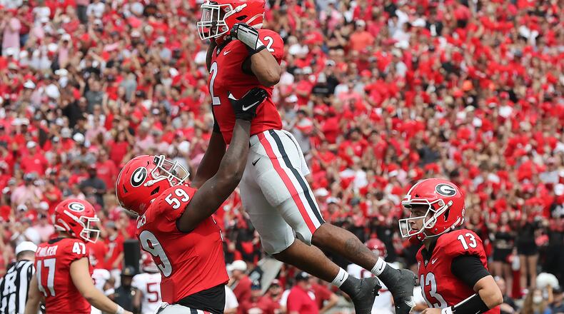 Georgia's offense is expected to get a lift this year with the return of sophomore Broderick Jones at left tackle. Jones (59) is shown hoisting running back Kendall Milton after Milton's touchdown gave the Bulldogs a 14-0 lead against Arkansas last October. Quarterback Stetson Bennett (13) also will be back for the Bulldogs. (Curtis Compton / Curtis.Compton@ajc.com)