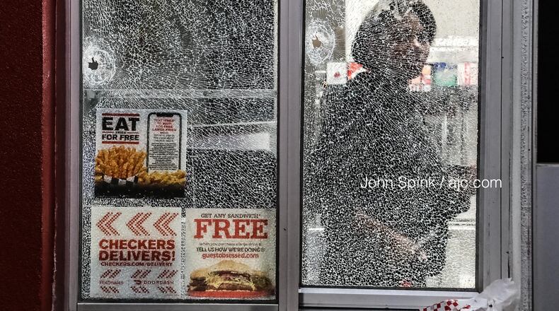 Bullet holes can be seen in the walk-up window of a Checkers restaurant on Candler Road after a shooting early Wednesday.
