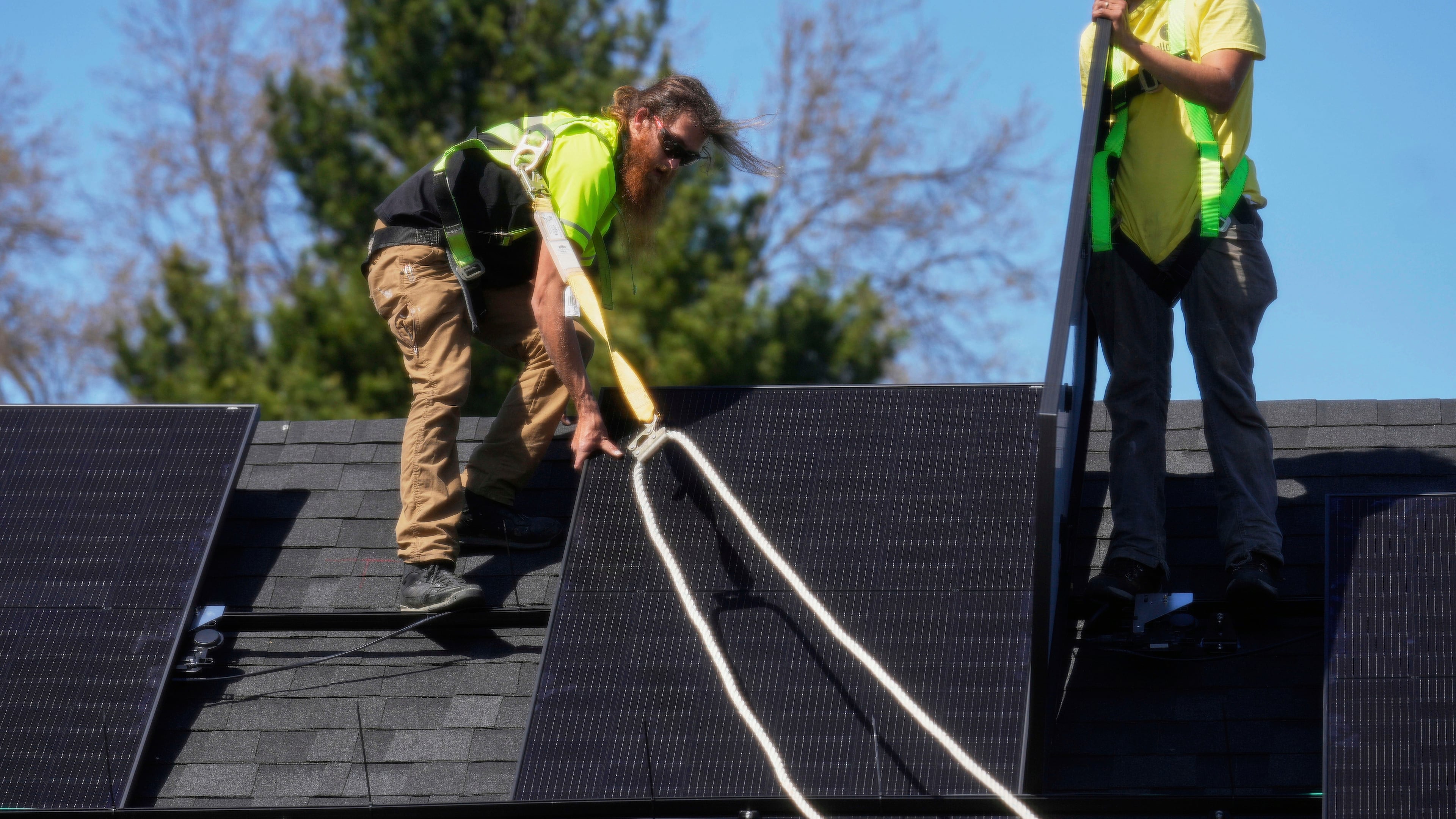 FILE - Theodore Tanczuk, left, and Brayan Santos, right, of solar installer YellowLite, work to put panels on a home in Lakewood, Ohio, April 16, 2025. (AP Photo/Sue Ogrocki, File)