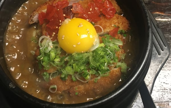 The baked katsu curry rice at Shoya Izakaya features a breaded pork cutlet and raw egg yolk that is mixed into the rice. (Christopher Hassiotis for the AJC)