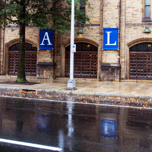 FILE - A woman walks by a Yale sign reflected in the rainwater on the Yale University campus in New Haven, Conn., Aug. 22, 2021. (AP Photo/Ted Shaffrey, File)