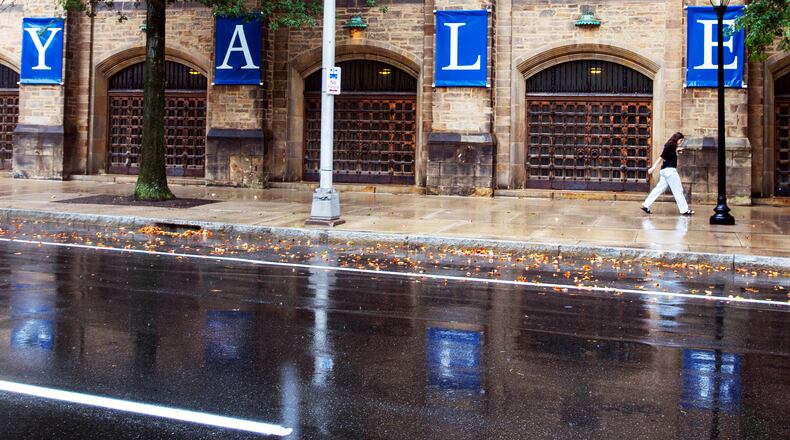 FILE - A woman walks by a Yale sign reflected in the rainwater on the Yale University campus in New Haven, Conn., Aug. 22, 2021. (AP Photo/Ted Shaffrey, File)
