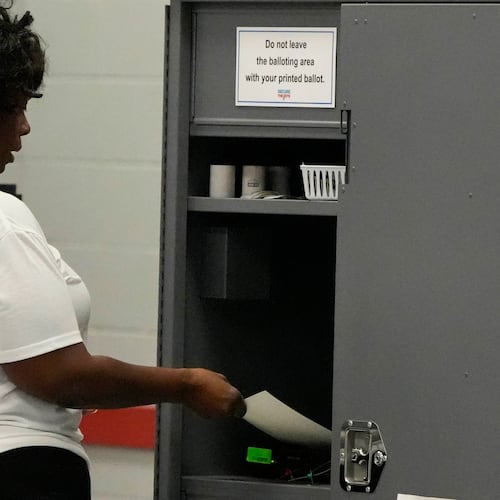 A woman places her paper ballot into a machine after voting in a runoff election at C.T. Martin Recreation Center, Tuesday, June 16, 2026, in Atlanta. (AP Photo/Mike Stewart)