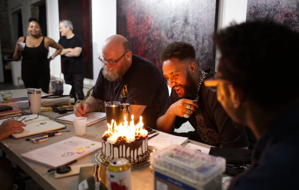 In a sign of the close community enjoyed by the High Contrast artists, a chocolate cake marked the birthdays of participants James Daniel (center) and Mariano Lino (front right) during the July session, with slices shared around the room. (Courtesy of Dustin Timbrook)