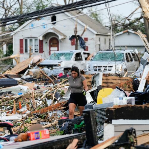 A woman walks among debris after a tornado struck Monday, July 27, 2026, in Menasha, Wis. (AP Photo/Kayla Wolf)