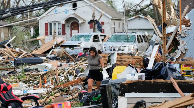 A woman walks among debris after a tornado struck Monday, July 27, 2026, in Menasha, Wis. (AP Photo/Kayla Wolf)