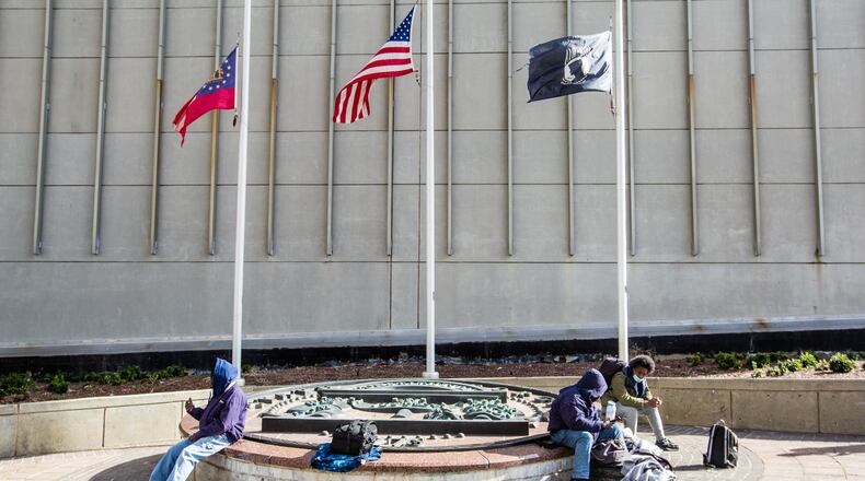People gather on the Georgia State seal at the corner of Peachtree Street and Marietta Street in Atlanta in January. A new city program aims to provide housing for 800 homeless individuals. (Jenni Girtman for The Atlanta Journal-Constitution)