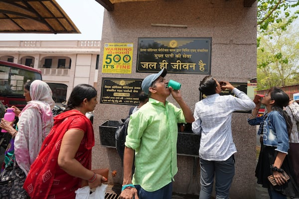 People drink water at a distribution center at a bus stop in Ahmedabad, India, Wednesday, April 2, 2025. (AP Photo/Ajit Solanki)