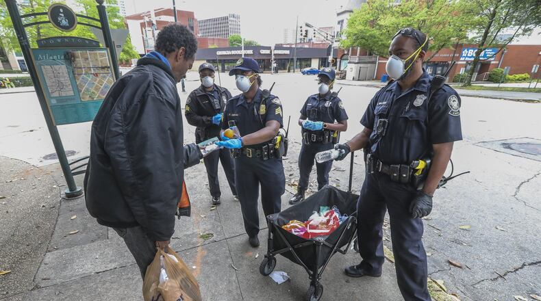 Atlanta Police Department officers distribute masks to the homeless at Hurt Park downtown on Friday, April 24, 2020. JOHN SPINK/JSPINK@AJC.COM