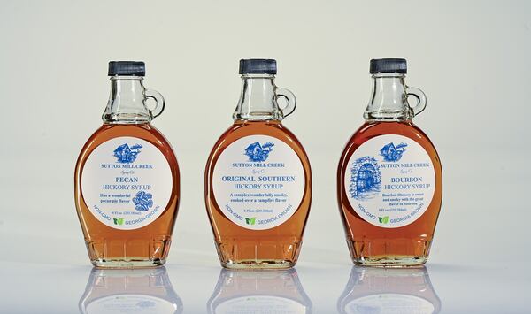 Three bottles of Sutton Mill Creek hickory syrup on a white background