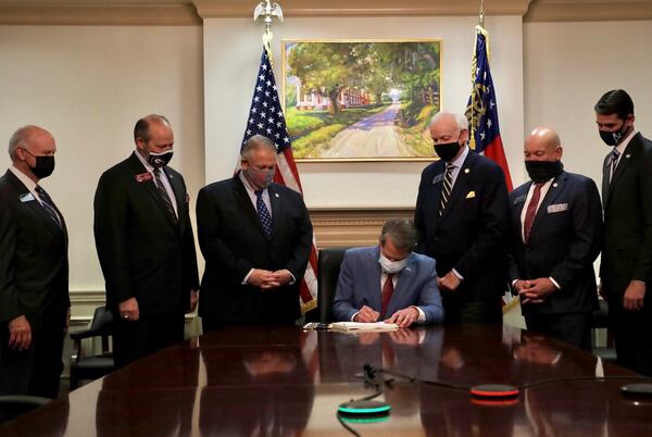 Gov. Brian Kemp signs the elections overhaul into law at the Capitol, flanked by legislative leaders.