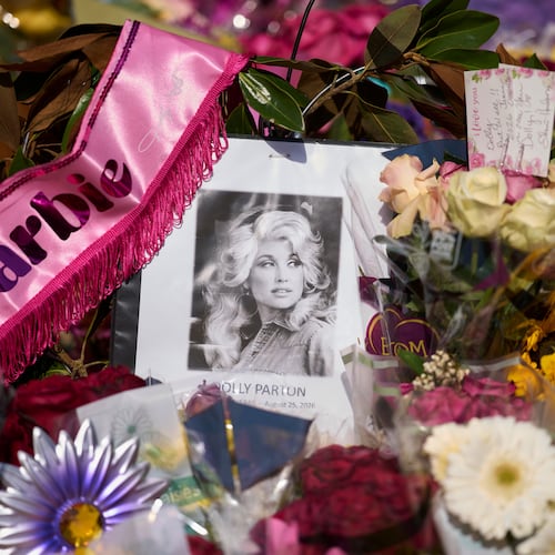 A portrait of the late Dolly Parton surrounded by flowers and cards in a memorial sits outside her home Thursday, Aug. 27, 2026, in Brentwood, Tenn. (AP Photo/George Walker IV)