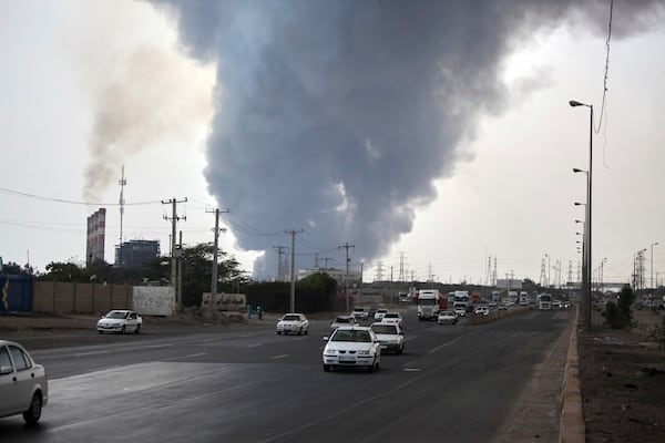 In this photo provided by Islamic Republic News Agency, IRNA, a black smoke rises in the sky as vehicles drive on the road after a massive explosion near the southern port city of Bandar Abbas, Iran, Saturday, April 26, 2025. (Mohammad Rasoul Moradi/IRNA via AP)