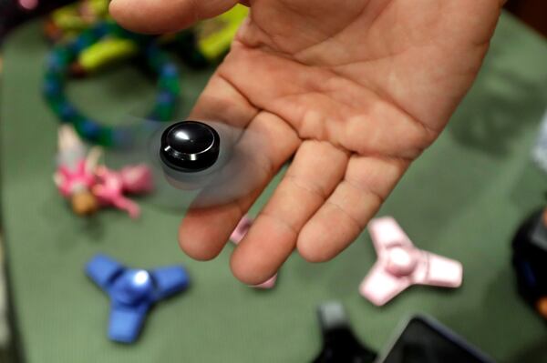FILE - Funky Monkey Toys store owner Tom Jones plays with a fidget spinner in Oxford, Mich, Thursday, May 11, 2017. (AP Photo/Carlos Osorio, File)