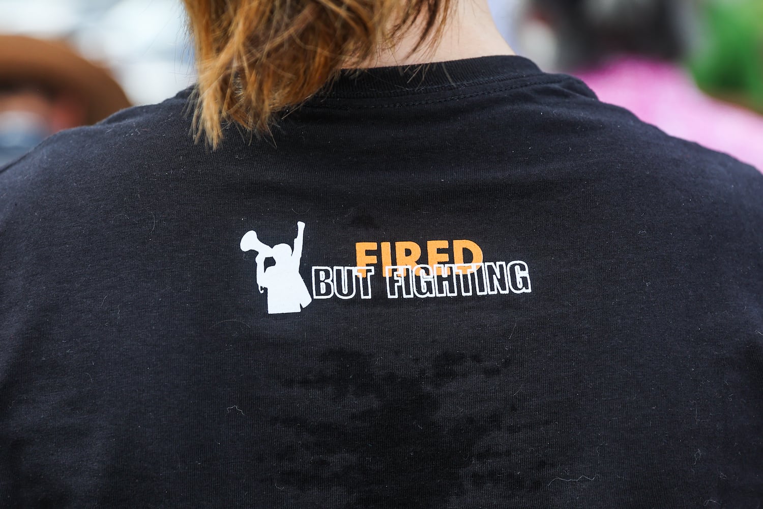 An activist wears a ‘fired but fighting’ shirt outside of the CDC in Atlanta on Wednesday, June 25, 2025.  As Health and Human Services Secretary Robert F. Kennedy Jr. purged and reconstituted CDC vaccine advisory panel, ACIP, convenes for the first time, CDC advocates gather to protest on the dangers to health. (Abbey Cutrer / AJC)