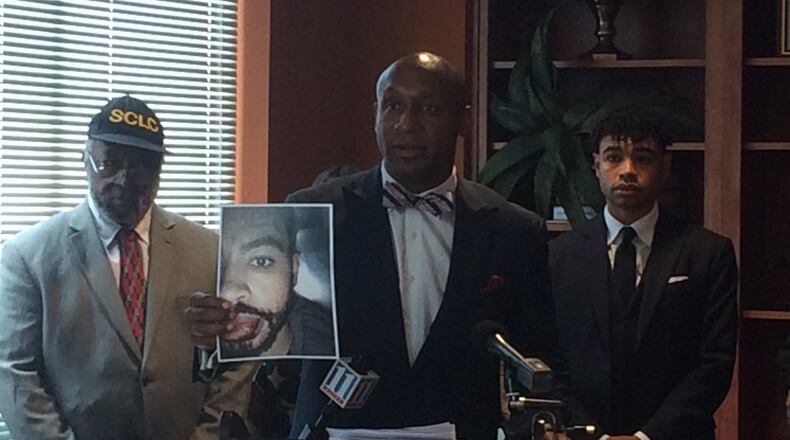 Attorney Mawuli Davis holds a photo of client Corey Toole’s injuries. Toole is suing the city of Atlanta and police officers, accusing them of forcibly throwing him to the ground and unlawfully arresting him. (RAISA HABERSHAM / RAISA.HABERSHAM@AJC.COM)