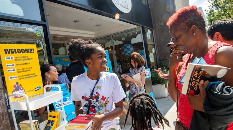 MoveOn Political Action's Banned Bookmobile distributed free banned books at the kickoff of National Banned Book Week in Decatur, where Kimora Bernard (from left), 12, her sister, Kimiyah, 5, and grandmother Carmen Bernard (right) of Stone Mountain pick out a few of the banned books that cannot be checked out at some public school libraries on Sunday, Oct. 1, 2023, at Little Shop of Stories in the Decatur Square. (Jenni Girtman for The Atlanta Journal-Constitution.)