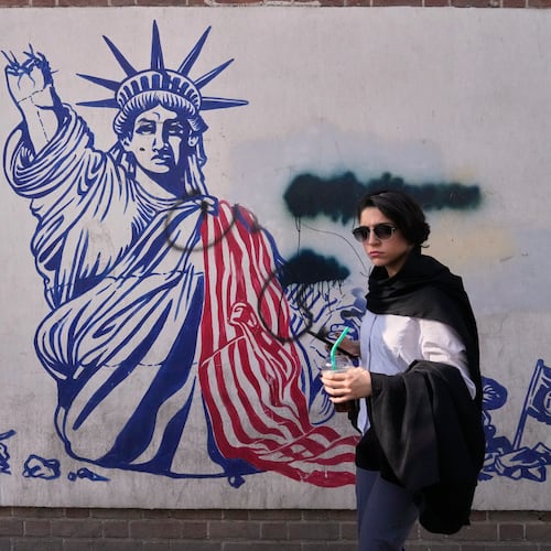 A woman walks past an anti-American mural on the wall of the former U.S. Embassy, now a museum, in Tehran, Iran, Friday, June 12, 2026. (AP Photo/Vahid Salemi)