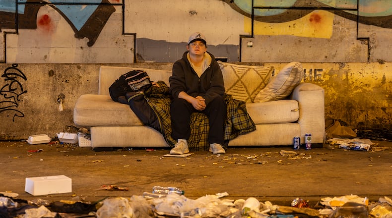 Xhexania Xander sits on a couch at a homeless encampment on Bell Street on Friday, March 6, 2026, in Atlanta. The site near Grady Memorial Hospital, just over a mile from Mercedes-Benz Stadium, has become a public health issue. (Ben Hendren for the AJC)