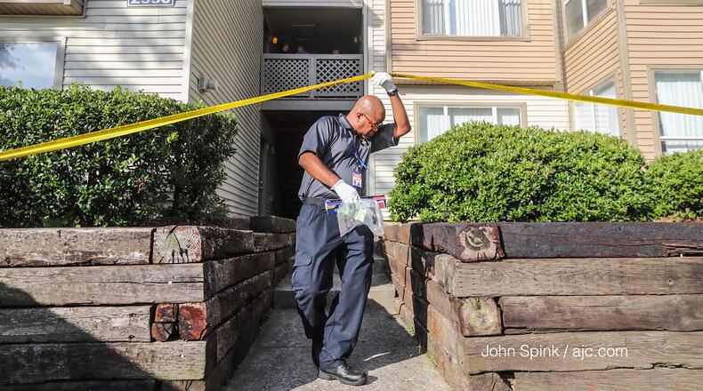 A Gwinnett police investigator gathers evidence at an apartment off Satellite Boulevard after a woman was killed in a domestic shooting Tuesday morning.
