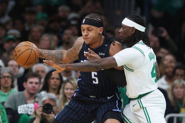 Orlando Magic's Paolo Banchero (5) keeps the ball away from Boston Celtics' Jrue Holiday (4) during the first half in game 1 of a first-round NBA playoff basketball series Sunday, April 20, 2025, in Boston. (AP Photo/Michael Dwyer)