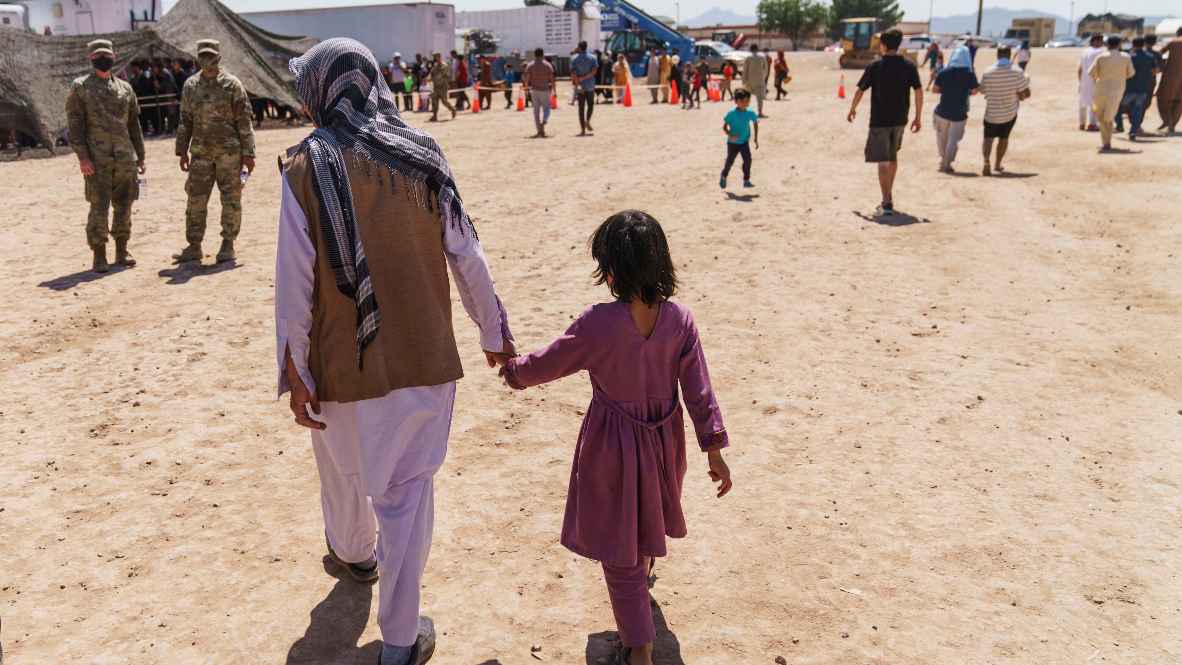 FILE - A man walks with a child through Fort Bliss' Doña Ana Village where Afghan refugees are being housed, in New Mexico, Friday, Sept. 10, 2021. (AP Photo/David Goldman, File)