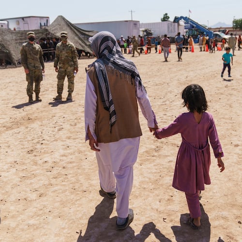 FILE - A man walks with a child through Fort Bliss' Doña Ana Village where Afghan refugees are being housed, in New Mexico, Friday, Sept. 10, 2021. (AP Photo/David Goldman, File)