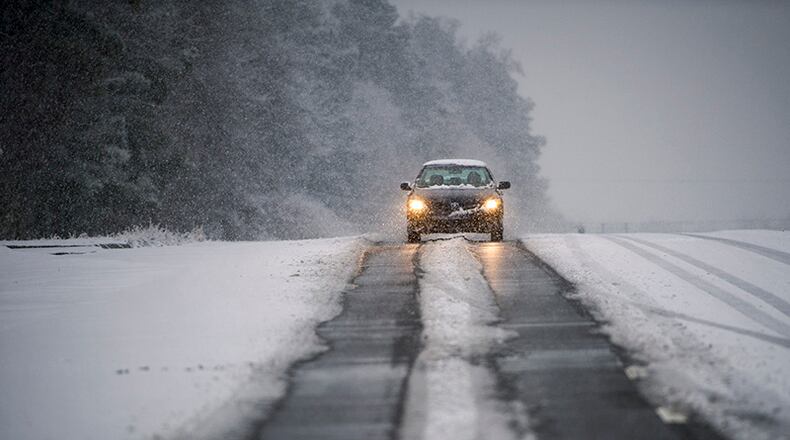 A motorist rides along the tire paths cleared of snow on Georgia state Route 141.