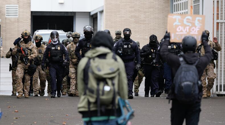 FILE - People protest outside a U.S. Immigration and Customs Enforcement facility as law enforcement officers walk out of the gates to guard vehicles leaving the facility on Oct. 11, 2025, in Portland, Ore. (AP Photo/Jenny Kane, File)