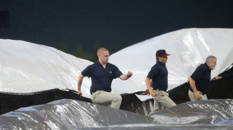 Members for the Atlanta Braves grounds crew work to cover the infield as rain begins to fall in the fourth inning of a baseball game against the New York Mets Thursday, May 4, 2017, in Atlanta. (AP Photo/John Bazemore)