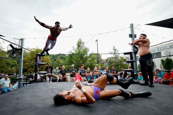 Jay Alpha Miller jumps from the third cord to land on Stunt Marshall while Apollo Prince watches during a wrestling match at New Realm Brewing on Sunday, August 31, 2025, in Atlanta. (Miguel Martinez/ AJC)