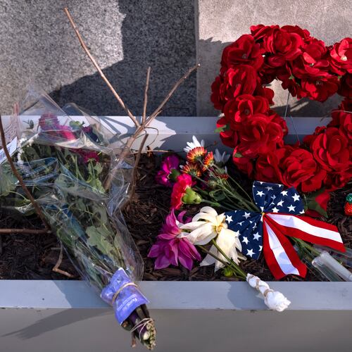 A small memorial of flags, flowers, other items are seen in a planter, Friday, Nov. 28, 2025, near the site where two National Guard members were shot in Washington. (AP Photo/Mark Schiefelbein)