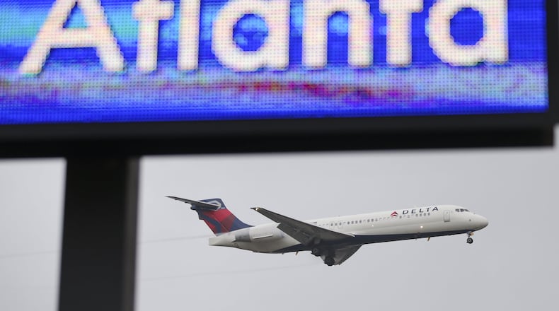A Delta jet lands, while an electronic board at Hartsfield-Jackson welcomes visitors to Atlanta. JOHN SPINK / JSPINK@AJC.COM