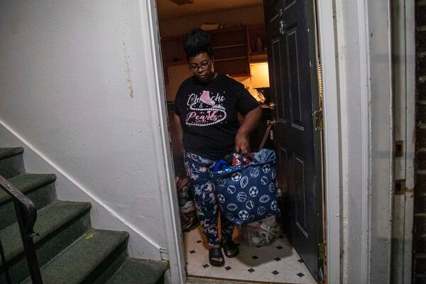 Tranisha Wilcox carries trash bags, totes and laundry baskets stuffed with her family's belongings to her car on the evening she moved out of Pavilion Place. She could not find an apartment that she could afford by her eviction deadline, so in October, she and her two sons moved to a hotel off Fulton Industrial Boulevard in southwest Fulton County. (Alyssa Pointer / AJC 2021)