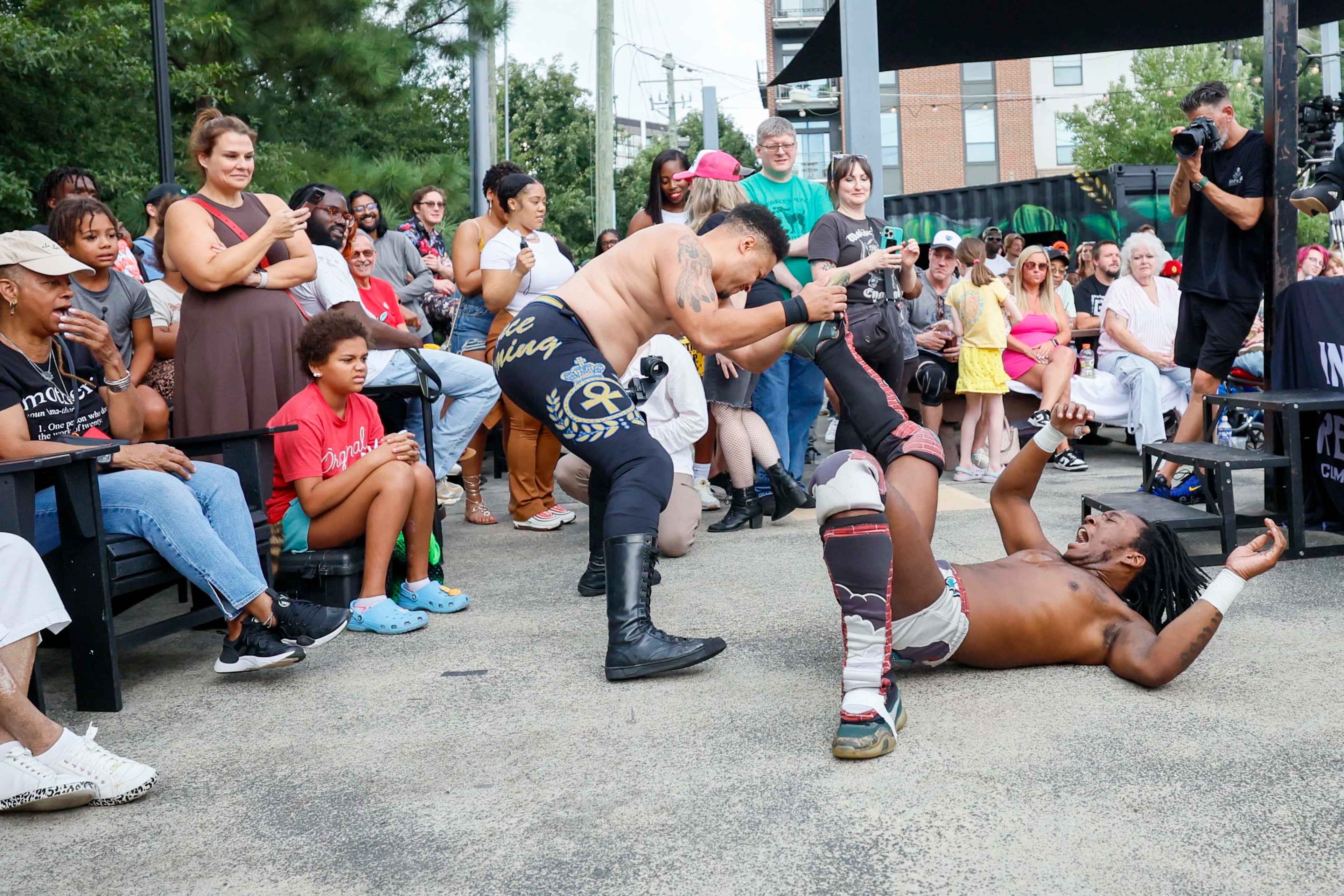 Apollo Prince, left, fights with DJ Smoke outside the ring while the crowd watches during a wrestling match at New Realm Brewing on Sunday, August 31, 2025, in Atlanta. Deep South Wrestling has been hosting free events since 2022, fully embracing what we call "unabashed entertainment." (Miguel Martinez/AJC)